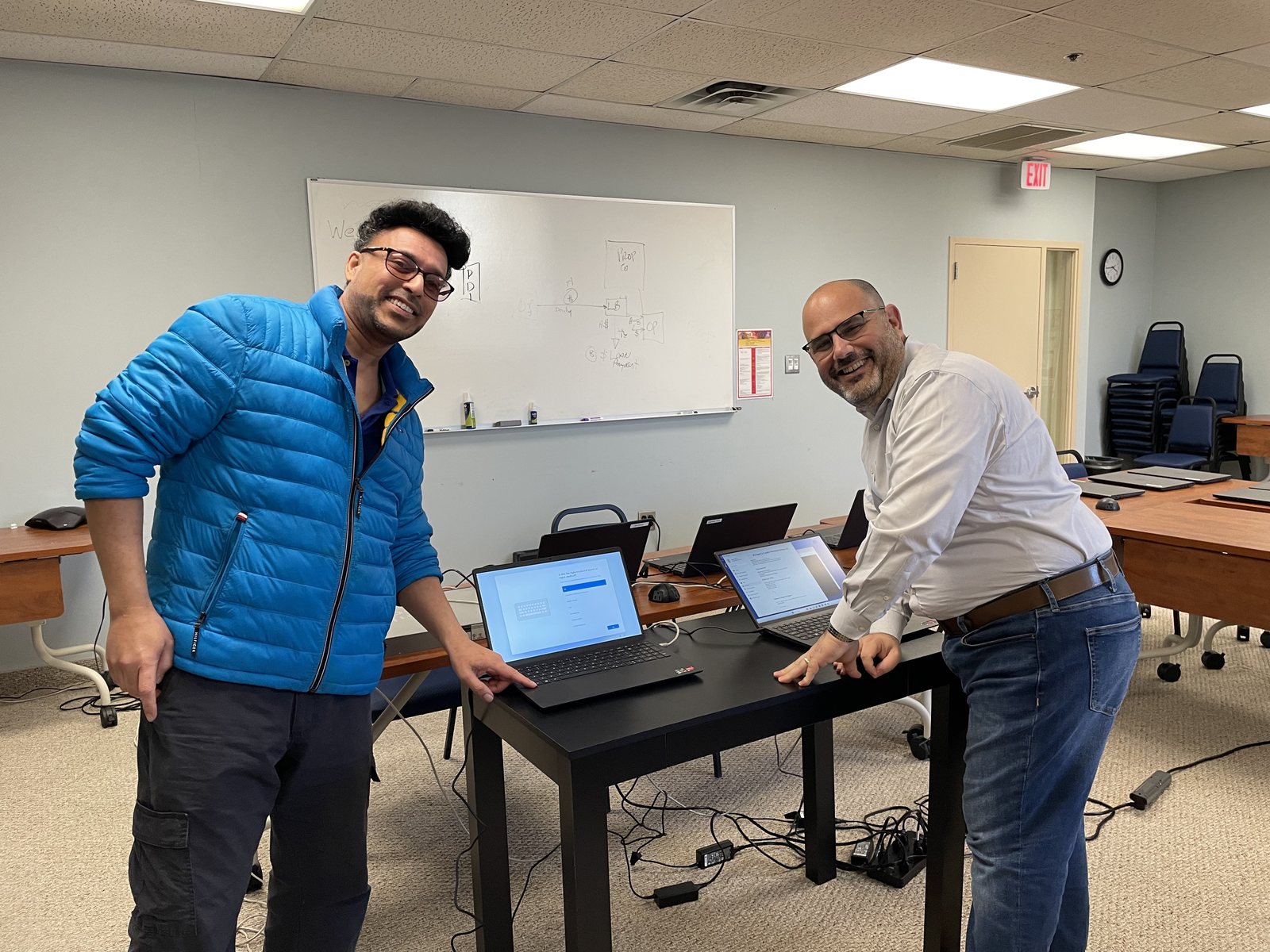 Two people setting up a row of new laptops in a training room at Capitol Petroleum Group