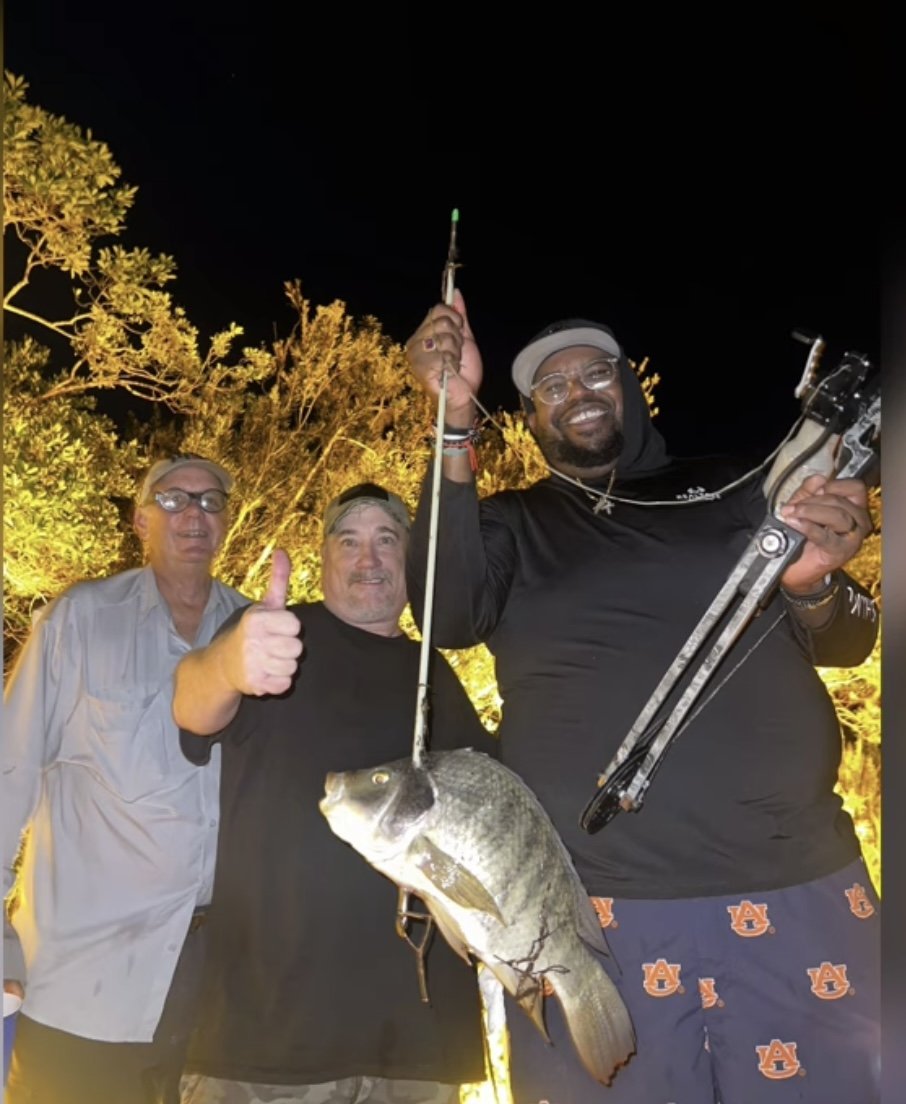 Three of the night's crew holding up a fish under the lights