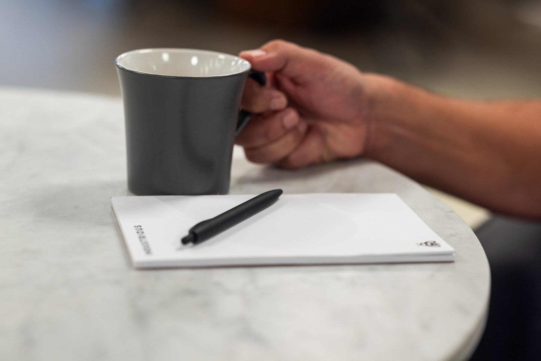 A hand, a cup, and a notebook